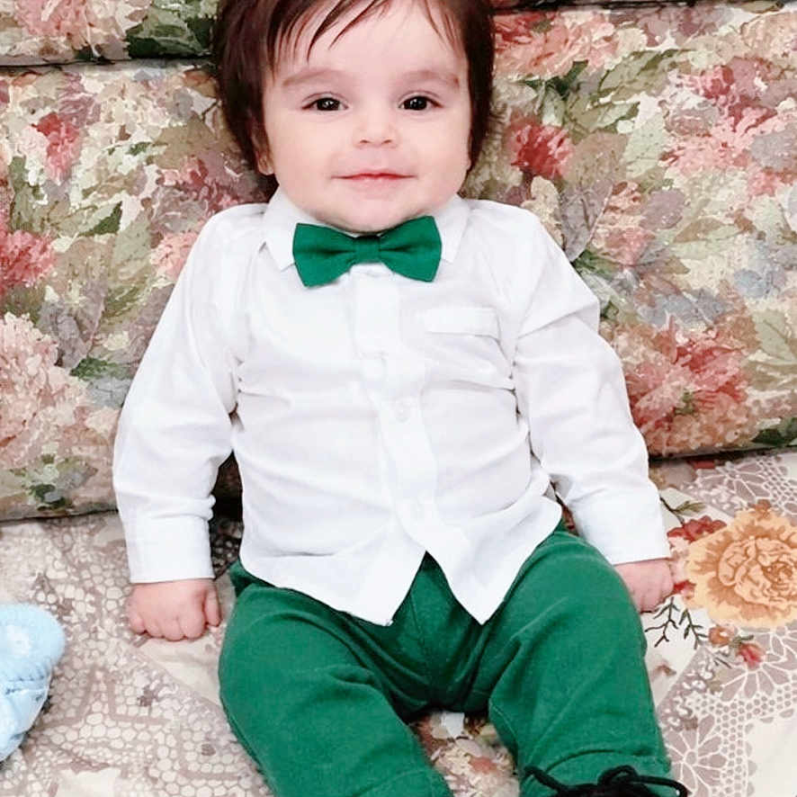 Miran is registered to the contest to win money with this photo: baby, child, infant, portrait, sitting, couch, floral, bow_tie, white_shirt, green_trousers, black_shoes, fashion, formalwear, smiling, indoors, furniture, closeup, cute, photography, family_photo