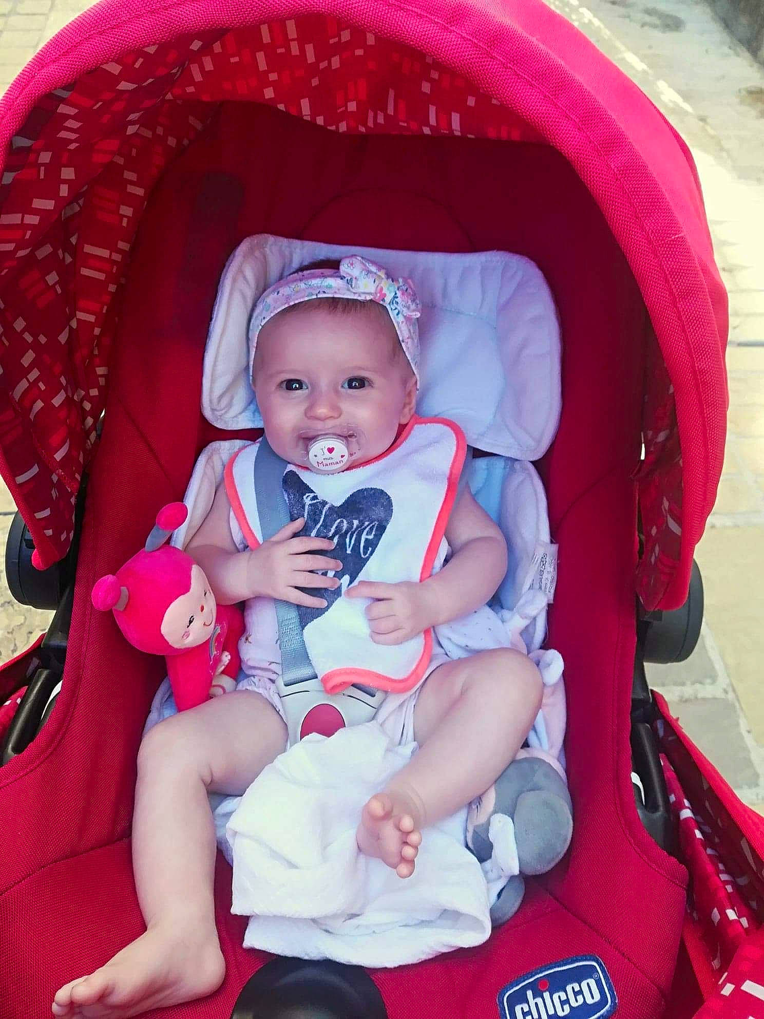 Julia participe au concours pour gagner de l'argent avec cette photo : baby, baby_carriage, baby_carrier, baby_in_car_seat, baby_products, car_seat, child, comfort, fun, headwear, joy, person, pink, product, sitting, skin, smile, toddler