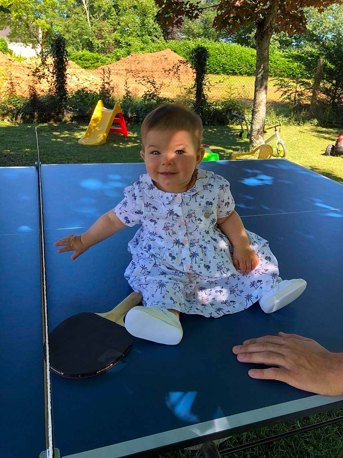 Maëlie a rejoint le concours — aidez-le/la à gagner de superbes lots ! baby_toddler_clothing, child, electric_blue, facial_expression, fun, grass, happy, joy, leisure, outdoor_play_equipment, person, plant, play, playground, recreation, shorts, sitting, t_shirt, toddler, trampolining_equipment_and_supplies