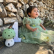 Delia joined the competition — help win amazing prizes! baby, child, girl, dress, green_dress, butterfly, mushroom_ornament, stone_wall, rock_wall, outdoor, sunlight, concrete, number_one, birthday, celebration, portrait, sitting, cute, nature, decor