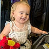 Lola is registered to the contest to win money with this photo: baby, background, car_seat, child, clothing, cute, dress, ghost_pattern, hair_tie, happy, holding, indoors, person, playful, pony_tail, red_toy, smiling, stuffed_toy, toddler, yellow_toy