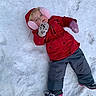 Lola is registered to the contest to win money with this photo: child, cold_weather, cute, footwear, fun, gloves, happy, lying_down, mittens, outdoor, person, pink_earmuffs, playful, red_jacket, snow, snow_boots, snowy_ground, toddler, winter, winter_clothing