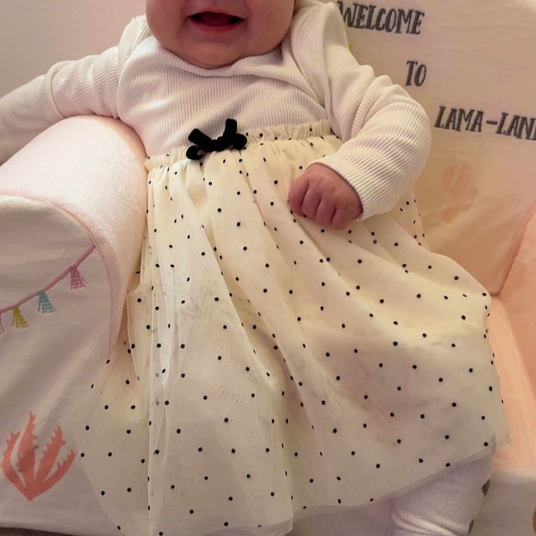 Aïtana a rejoint le concours — aidez-le/la à gagner de superbes lots ! baby, child, cozy, cushioned_chair, cute, decor, floor, happy, indoor, infant, polka_dot, portrait, sitting, skirt, smile, text_on_chair, toddler, turban_hat, white_clothing, wood_flooring
