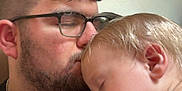 Ezekiel is registered to the contest to win money with this photo: man, child, toddler, sleeping, glasses, beard, kiss, affection, intimacy, closeup, indoor, portrait, love, family, gentle, rest, peaceful, casual_clothing, head, skin