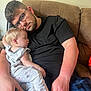 toddler, man, sleeping, glasses, couch, indoor, casual_clothing, child, resting, beard, black_shirt, light_hair, holding, comfort, family, portrait, relaxation, human, seated, affection