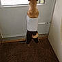 dog, pet, clothing, tank_top, pants, indoor, carpet, door, window, tail, standing, brown, grass, sidewalk, curious, small_dog, animal, looking_out, back_view, cute
