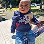 american_flag_pattern, baby, background, casual_clothing, child, daytime, expression, hand, hoodie, jeans, outdoor, park, people, person, sneakers, sunlight, table, toddler, trees, walking