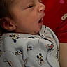 baby, infant, sleepy, yawning, mickey_mouse, onesie, clothing, cute, person, portrait, indoor, child, face, head, red_background, patterned_clothing, newborn, small, human, cozy