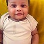 baby, infant, smiling, onesie, drool, yellow_pillow, curly_hair, cute, chubby, indoor, portrait, child, happy, sitting, skin, face, hand, young, closeup, cozy