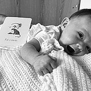 Suzanne participe au concours pour gagner de l'argent avec cette photo : baby, infant, smile, knitted_blanket, face, hand, card, text, black_and_white, happy, lying_down, young_child, portrait, cozy, indoors, cute, head, clothing, skin, closeup