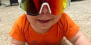 Nathaniel is registered to the contest to win money with this photo: baby, carpet, child, clothing, crawling, cute, face, hand, happy, head, indoor, infant, orange_onesie, person, playful, reflection, skin, smiling, sunglasses, young