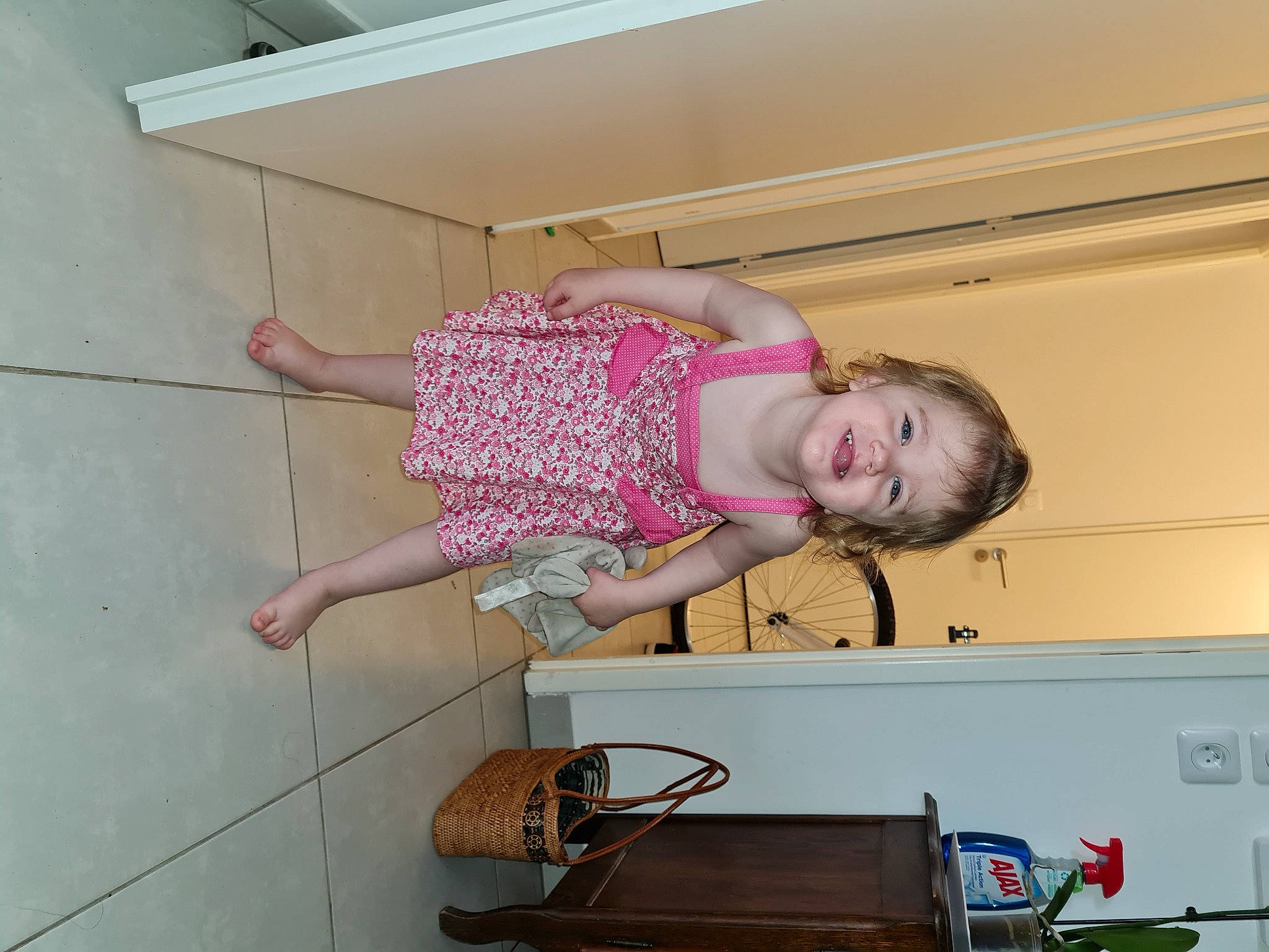 Lylou participe au concours pour gagner de l'argent avec cette photo : baby_toddler_clothing, child, floor, flooring, foot, fun, hardwood, home_appliance, homemaker, human_leg, joy, luggage_and_bags, pattern, person, pink, room, sandal, smile, thigh, toddler