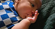 Isaias is registered to the contest to win money with this photo: baby, bald, blanket, blue_clothing, candid, checkered_pattern, child, close_up, cozy, ear, eyes, face, finger, hand, indoor, infant, lying_down, portrait, safe, sucking_finger
