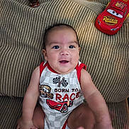Isaias is registered to the contest to win money with this photo: baby, bare_feet, cars_theme, child, couch, cushion, eyes, face, happy, home, indoors, infant, onesie, portrait, race_cars, red_clothing, sitting, smiling, striped_fabric, toy_car