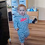 toddler, child, indoor, toy_car, clothing, hoodie, pants, barefoot, flooring, storage_bins, box, water_bottles, wooden_floor, person, home, walking, face, blue_eyes, short_hair, casual