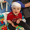 Charlie is registered to the contest to win money with this photo: toddler, child, medical, electrodes, gloves, toys, red_shirt, indoor, person, play, blue_wall, mirror, table, lamp, hand, face, headband, colorful, smile, seated