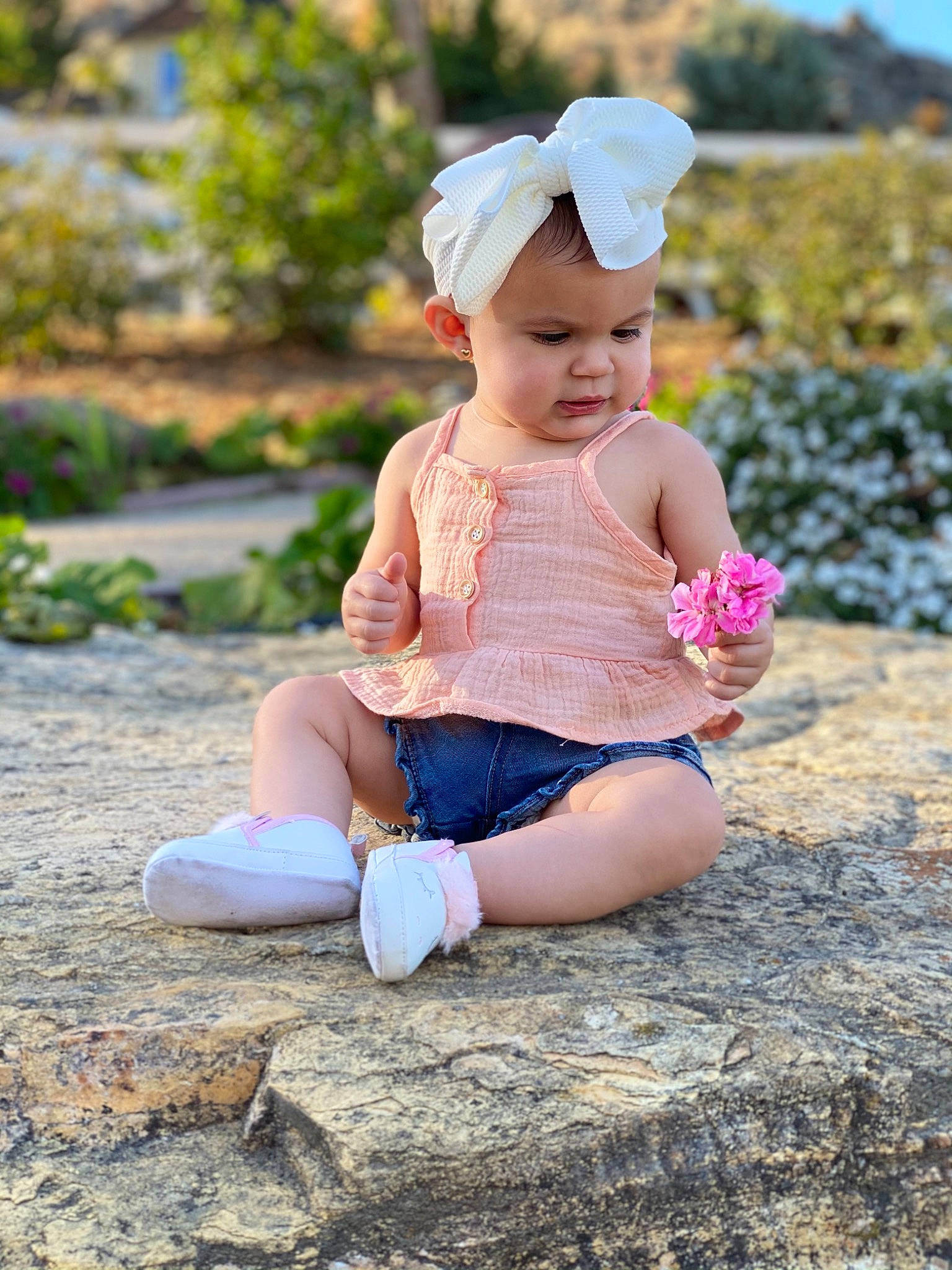 Jessica is registered to the contest to win money with this photo: baby, baby_toddler_clothing, cap, child, fashion_accessory, foot, grass, happy, hat, human_leg, landscape, leisure, people_in_nature, person, pink, plant, sitting, skin, sleeve, thigh