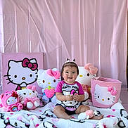 Azalea is registered to the contest to win money with this photo: baby, child, hello_kitty, plush_toys, pink, smiling, sitting, blanket, stuffed_animals, cute, portrait, indoor, decor, toy, person, head, clothing, hair_ties, basket, happy