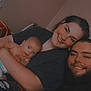 baby, child, couple, family, indoor, person, smiling, happy, face, head, arm, clothing, diaper, beard, hair, wall, window, pajamas, holding, seated
