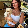 car, car_interior, car_seat, congratulatory_message, dog, fashion, fluffy, happy, holding_dog, outdoor_light, pet, phone_screenshot, portrait, puppies, puppy, seated, small_dog, smiling, text_overlay, woman