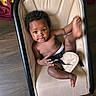 Nai'Ari is registered to the contest to win money with this photo: baby, beige, black_hair, blanket, child, curly_hair, cute, diaper, expression, floor, furniture, indoor, infant, kicking, person, playful, rocker, seat, smiling, wooden_floor
