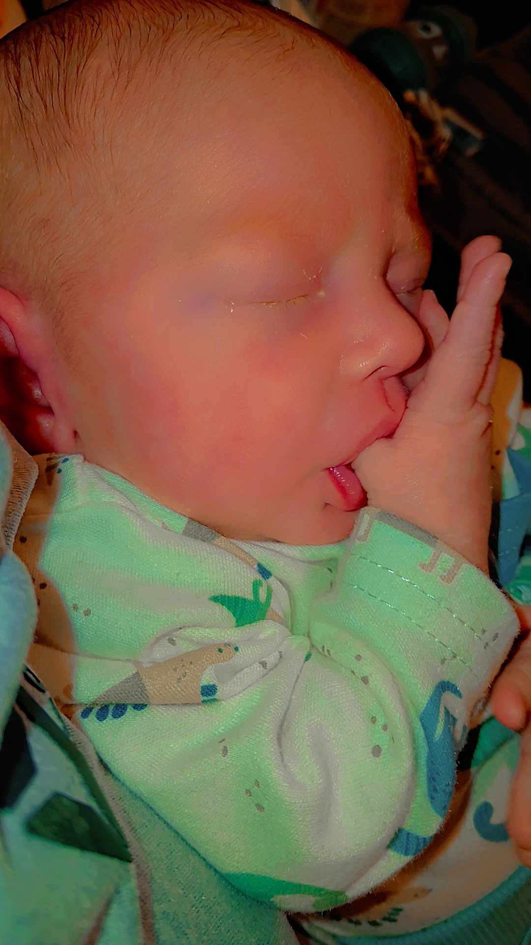 Cashton is registered to the contest to win money with this photo: baby, newborn, sleeping, thumb_sucking, onesie, dinosaur_pattern, infant, closeup, child, cute, peaceful, hand, face, skin, blanket, rest, young, portrait, comfortable, indoors