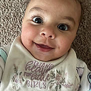 Kehlani Rodriguez is registered to the contest to win money with this photo: baby, smiling, face, eyes, bib, clothing, infant, cute, joy, happy, portrait, closeup, child, young, person, texture, fabric, carpet, expression, lying_down