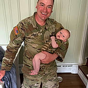 Ethan joined the competition — help win amazing prizes! soldier, baby, camouflage, uniform, smile, indoor, person, holding, military, child, home, floor, doorway, radiator, blanket, toddler, happy, portrait, man, infant