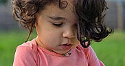 Sypha is registered to the contest to win money with this photo: background_blur, casual_clothing, child, curious, curly_hair, cute, daylight, face, grass, greenery, holding_object, innocence, nature, outdoor, person, pink_shirt, playing, portrait, toddler, young_child