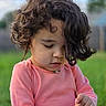 Sypha is registered to the contest to win money with this photo: child, toddler, curly_hair, pink_shirt, outdoor, grass, playing, nature, portrait, young_child, holding_object, daylight, casual_clothing, cute, curious, face, person, greenery, background_blur, innocence