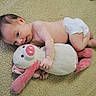 baby, infant, diaper, plush_toy, stuffed_animal, carpet, indoor, child, cute, soft_texture, pink, white, relaxed, lying_down, young_child, toy, toddler, person, cuddling, floor