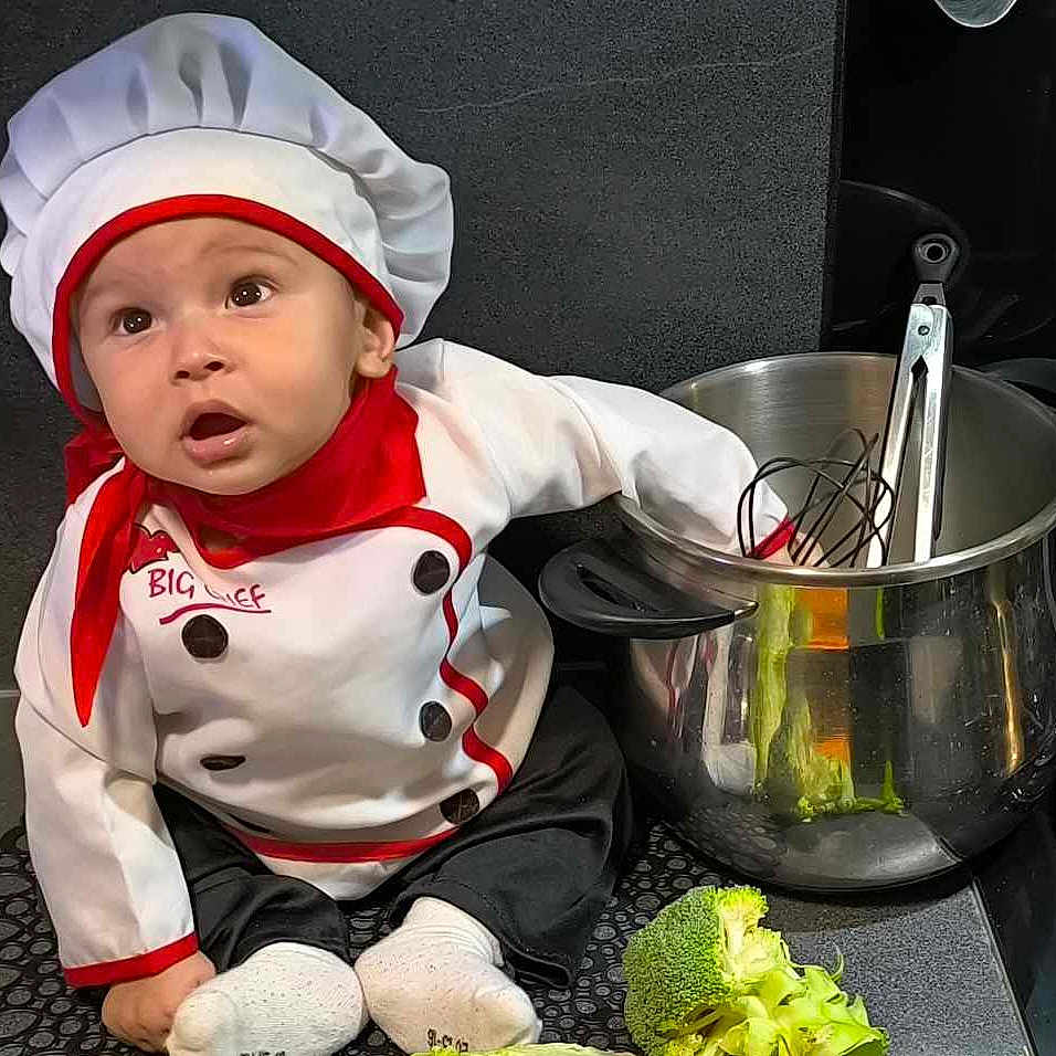 Ayssem participe au concours pour gagner de l'argent avec cette photo : baby, baby_chef, baby_clothing, black_pants, broccoli, chef_hat, cooking, cooking_utensils, countertop, curious_expression, cute, food, green_pepper, indoor, kitchen, lettuce, pot, red_scarf, vegetables, white_socks
