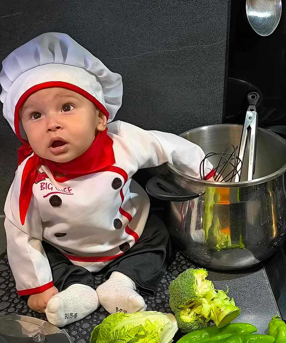 Ayssem participe au concours pour gagner de l'argent avec cette photo : baby, chef_hat, baby_chef, kitchen, pot, vegetables, broccoli, lettuce, green_pepper, cooking_utensils, baby_clothing, white_socks, countertop, curious_expression, black_pants, red_scarf, cooking, food, indoor, cute