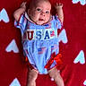 Violet joined the competition — help win amazing prizes! baby, infant, child, red_blanket, white_hearts, usa_outfit, flags, blue_clothing, red_bows, cute, smiling, lying_down, small_arms, small_legs, face, eyes, mouth, happy, indoor, portrait