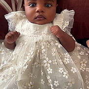 Miracle is registered to the contest to win money with this photo: adorable, baby, child, closeup, cushion, cute, dress, eyes, fabric, face, floral_pattern, hands, indoor, infant, pillow, portrait, soft_lighting, texture, white_dress, young