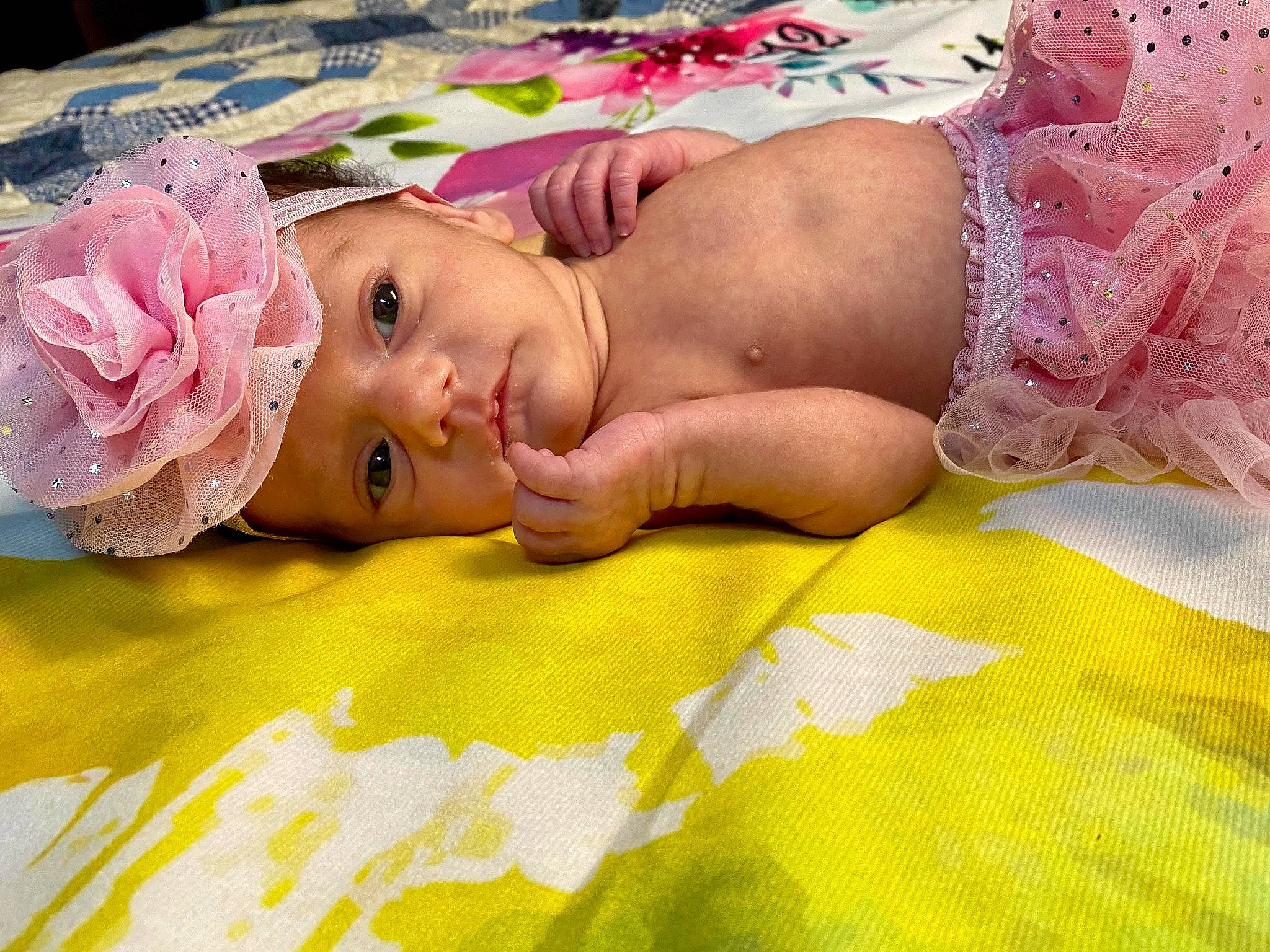 Naomi is registered to the contest to win money with this photo: baby, bed_sheet, bedding, bedtime, child, comfort, fashion_accessory, flooring, fun, grass, hair_accessory, happy, headpiece, headwear, linens, magenta, person, pink, room, skin