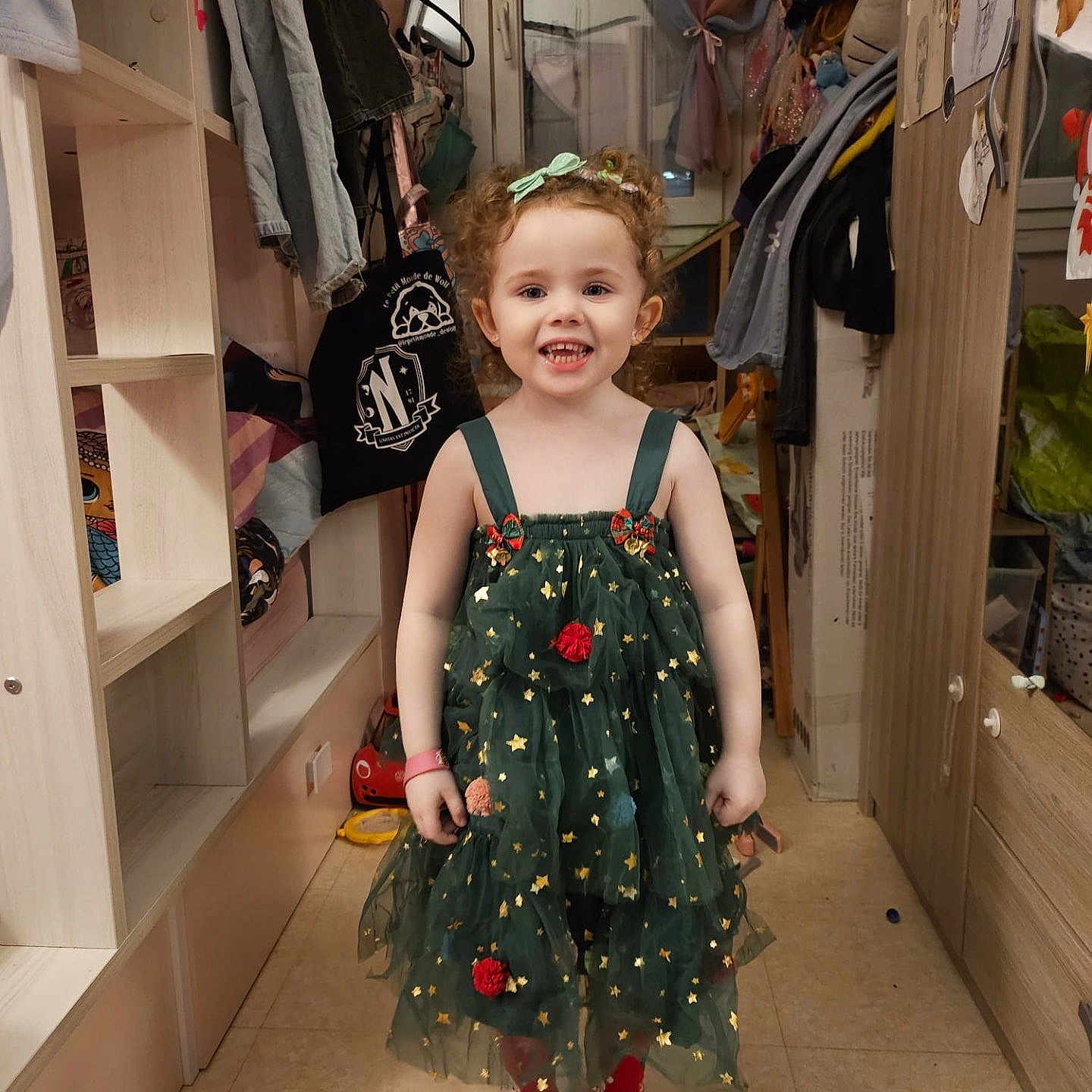 Calysta participe au concours pour gagner de l'argent avec cette photo : cabinet, child, clothes, curly_hair, curtains, dress, floor, furniture, girl, green_dress, hair_bow, happy, indoors, mirror, portrait, red_socks, room, smiling, standing, toys