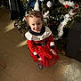 Calysta a rejoint le concours — aidez-le/la à gagner de superbes lots ! child, toddler, christmas_tree, holiday_outfit, red_dress, smiling, indoors, floor_tiles, decorations, festive, clapping, curly_hair, home, toy_ball, carpet, chair, furniture, celebration, happy, person