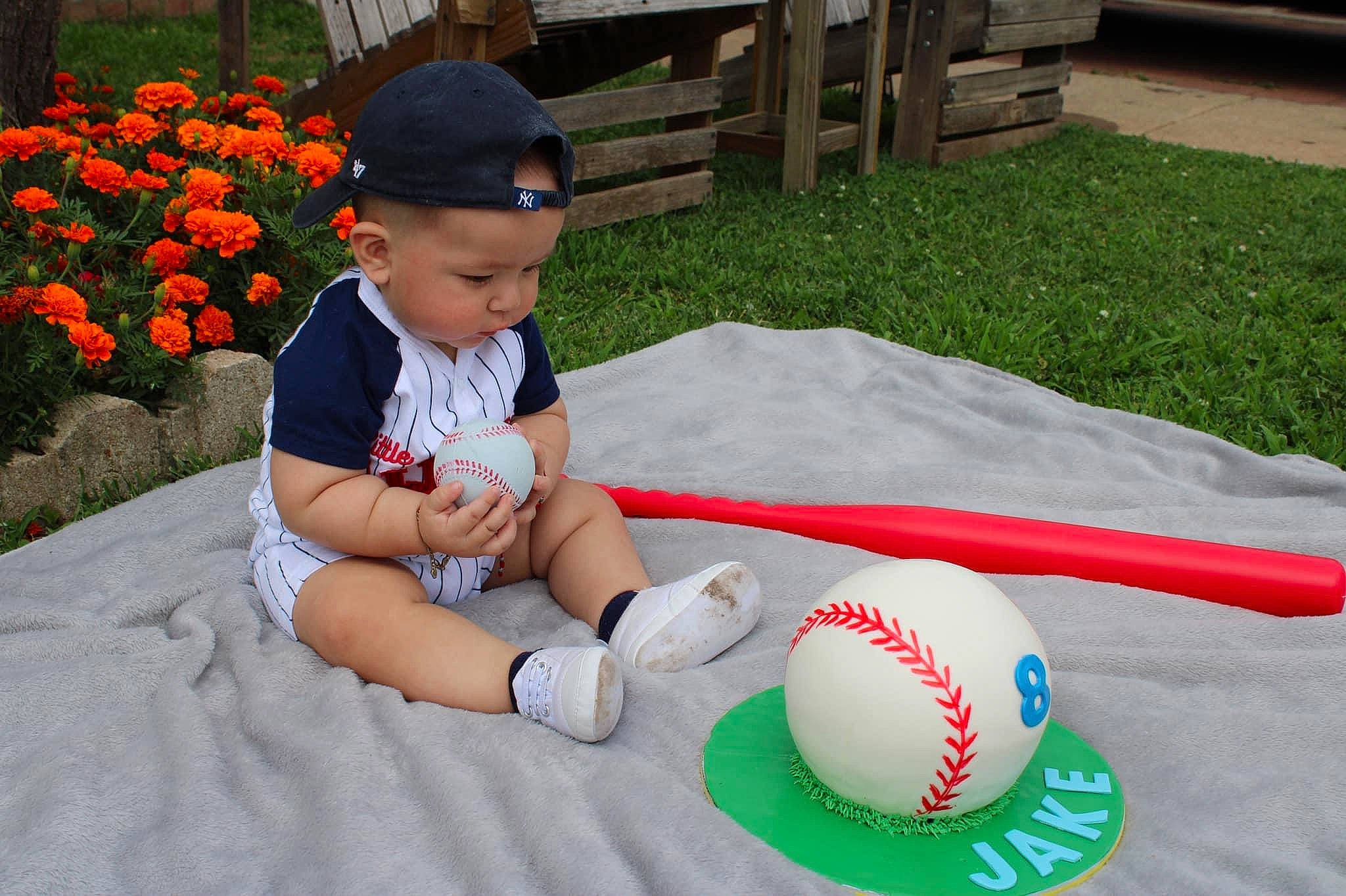 Jake is registered to the contest to win money with this photo: baby, baby_toddler_clothing, ball, ball_game, child, flower, football, fun, grass, hat, headwear, leisure, person, plant, playing_sports, shorts, sports_equipment, sports_toy, sunglasses, thigh