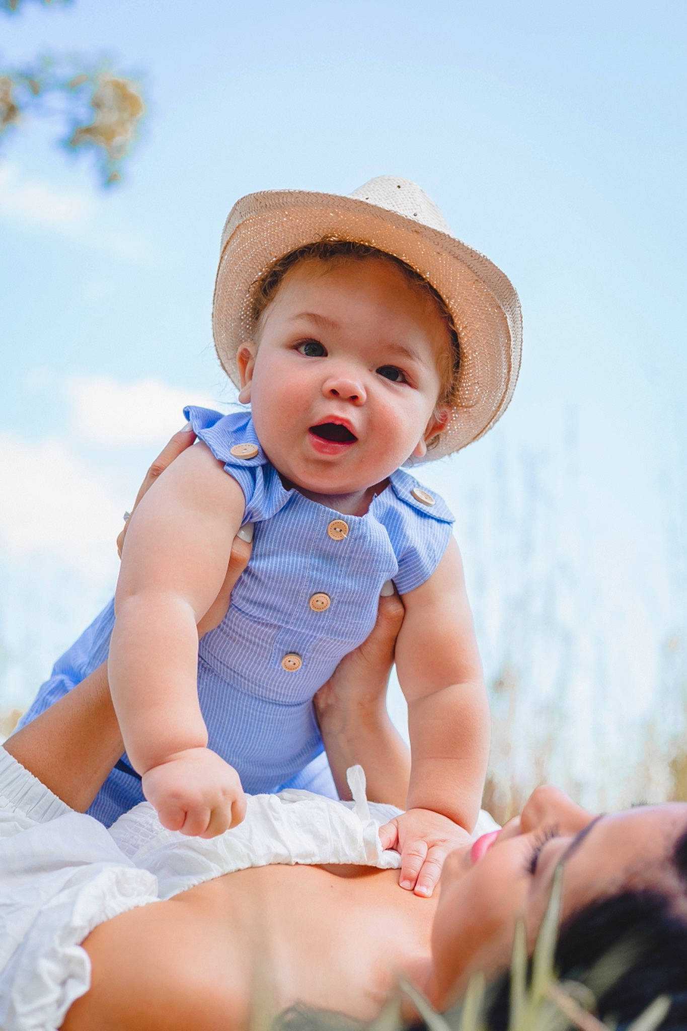 Rio is registered to the contest to win money with this photo: baby, baby_toddler_clothing, blond, cap, dress, eye, flash_photography, fun, grass, happy, hat, headgear, leisure, pattern, people_in_nature, person, sitting, skin, sky, sun_hat