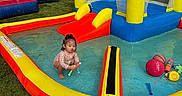Rose joined the competition — help win amazing prizes! child, toddler, baby, outdoor, backyard, splash_pad, inflatable_pool, water, water_slide, bounce_house, playground, toys, ball, basketball, summer, grass, residential, portrait, sitting, colorful