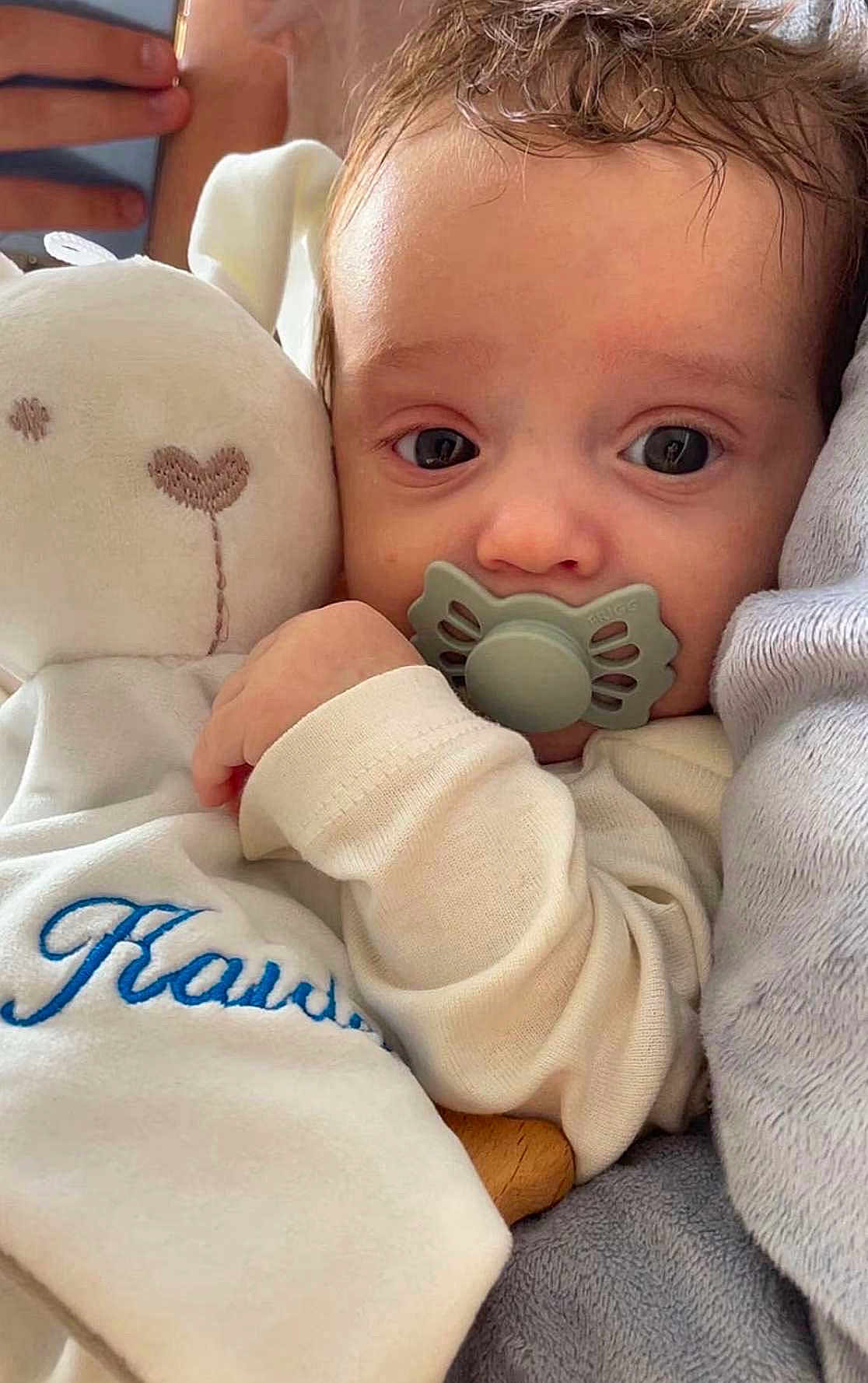Kaïden a rejoint le concours — aidez-le/la à gagner de superbes lots ! baby, blue_text, child, close_up, comfort, cozy, cuddling, cute, face, hand, indoors, infant, pacifier, phone, plush_toy, portrait, resting, sleepy, soft_texture, white_clothing