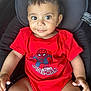 baby, child, infant, smile, red_clothing, spiderman, onesie, seat, cushion, curly_hair, cute, indoors, portrait, person, skin, hand, legs, bright, happy, looking_at_camera