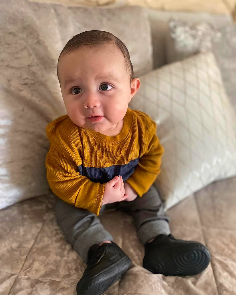 Carlos is registered to the contest to win money with this photo: baby_toddler_clothing, cheek, comfort, couch, dress, eye, face, facial_expression, floor, flooring, hair, head, human_body, leg, nose, person, skin, sleeve, smile, textile