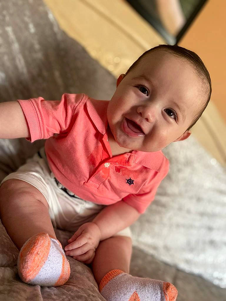 Carlos is registered to the contest to win money with this photo: baby, baby_toddler_clothing, ball, child, chin, eye, finger, floor, flooring, happy, human_body, joy, knee, leg, orange, person, skin, smile, sock, thigh