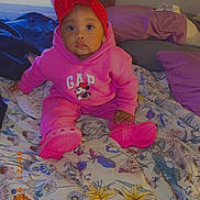 Zryiah joined the competition — help win amazing prizes! baby, child, pink_clothing, hoodie, headband, red_bow, sitting, bed, floral_bedspread, pillow, indoor, curtain, cute, footwear, expression, person, young_child, clothing, portrait, cozy