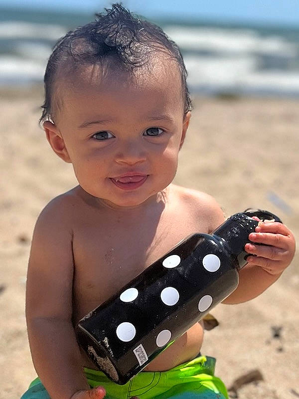 Nehemiah is registered to the contest to win money with this photo: beach, chest, communication_device, finger, fun, hairstyle, hand, happy, leisure, mobile_device, mobile_phone, people_in_nature, people_on_beach, person, photograph, portable_communications_device, sand, smile, summer, toddler
