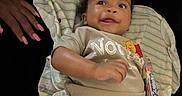 Nazavion is registered to the contest to win money with this photo: baby, child, infant, lying_down, striped_cloth, winnie_the_pooh, shirt, candy, hand, pink_nails, dark_background, smiling, cute, diaper, pants, person, closeup, happy, indoors, portrait
