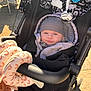 baby, stroller, beanie, jacket, plush_toy, sunlight, outdoor, child, cute, infant, face, person, warm_clothing, toy, seat, black, gray, patterned_fabric, pacifier, park