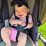 baby, child, smiling, stroller, black_bow, headband, pink_clothing, polka_dot, baby_harness, outdoor, grass, sunlight, cute, chubby_legs, infant, happy, person, seat, safety_strap, portrait